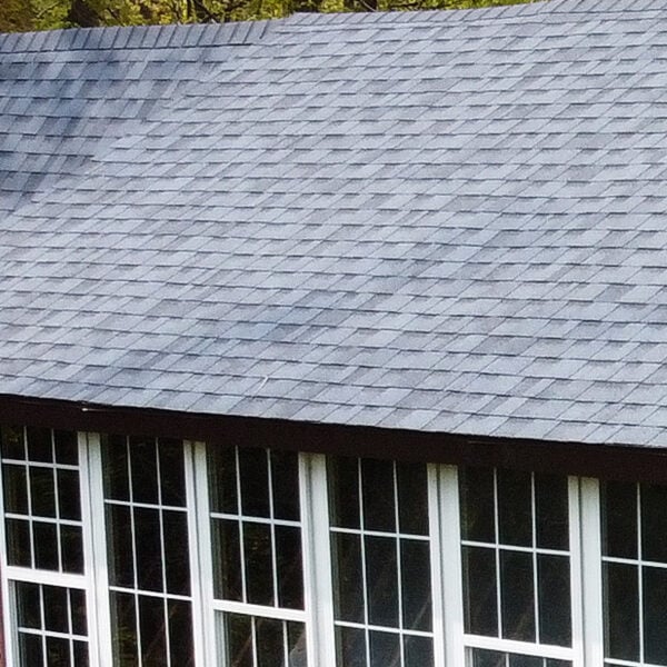 Roof of a house with grey shingles A house with a grey roof and red walls