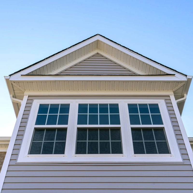 House with gray siding and white trim A house with gray siding and white trim under a clear blue sky.