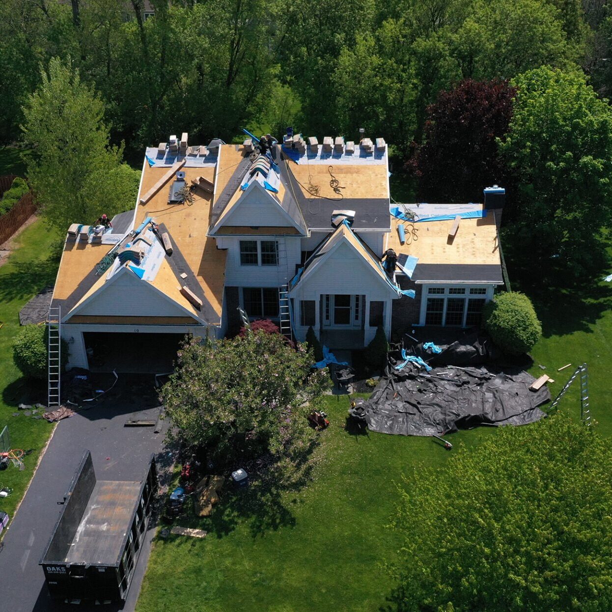 Large House with Roofing Work in Progress Aerial view of a large house with roofing work. The house has multiple gables and a large yard.