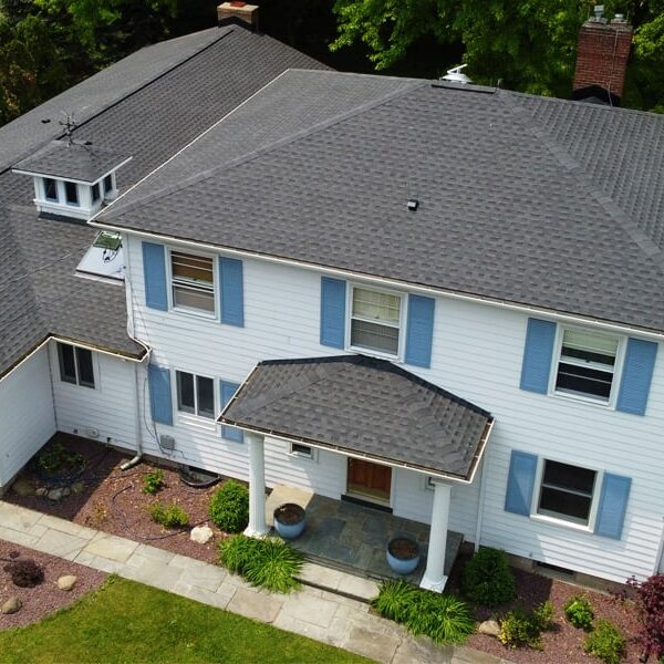 Aerial View of a Large White House Large white house with blue shutters and gray roof. Aerial view of a suburban home.