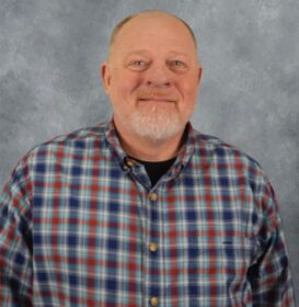 A man with a white goatee smiles