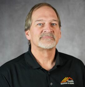Man with a goatee wearing a black polo shirt with a logo.