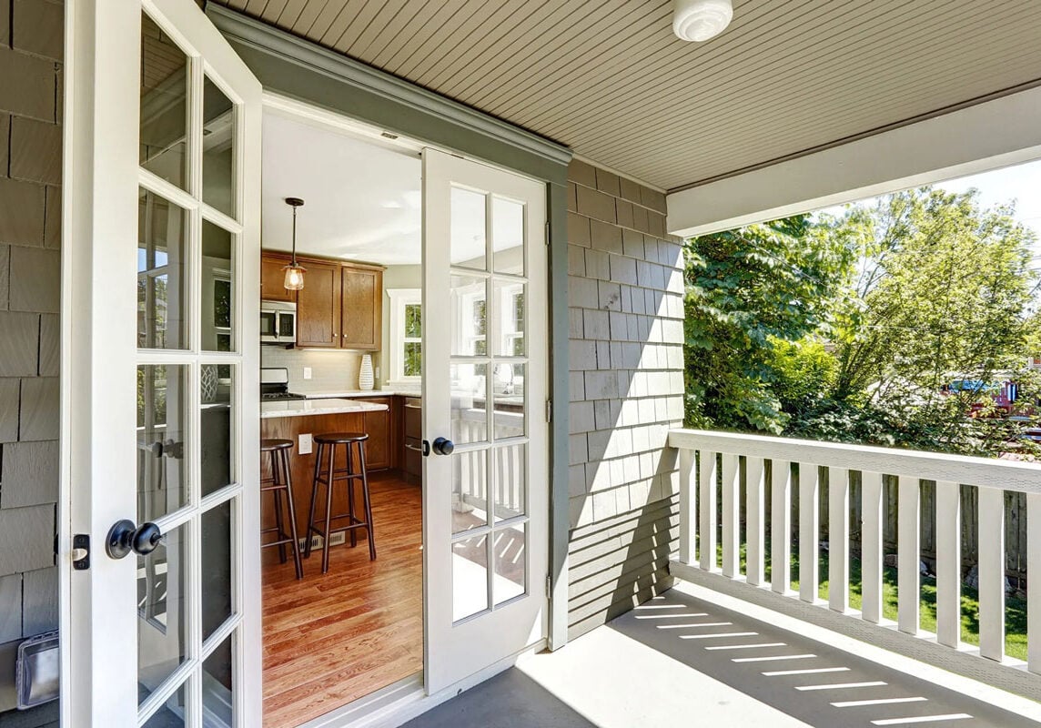 Screened in porch with white door and kitchen view Screened in porch with white door and kitchen view. The porch has a white railing and a view of trees.
