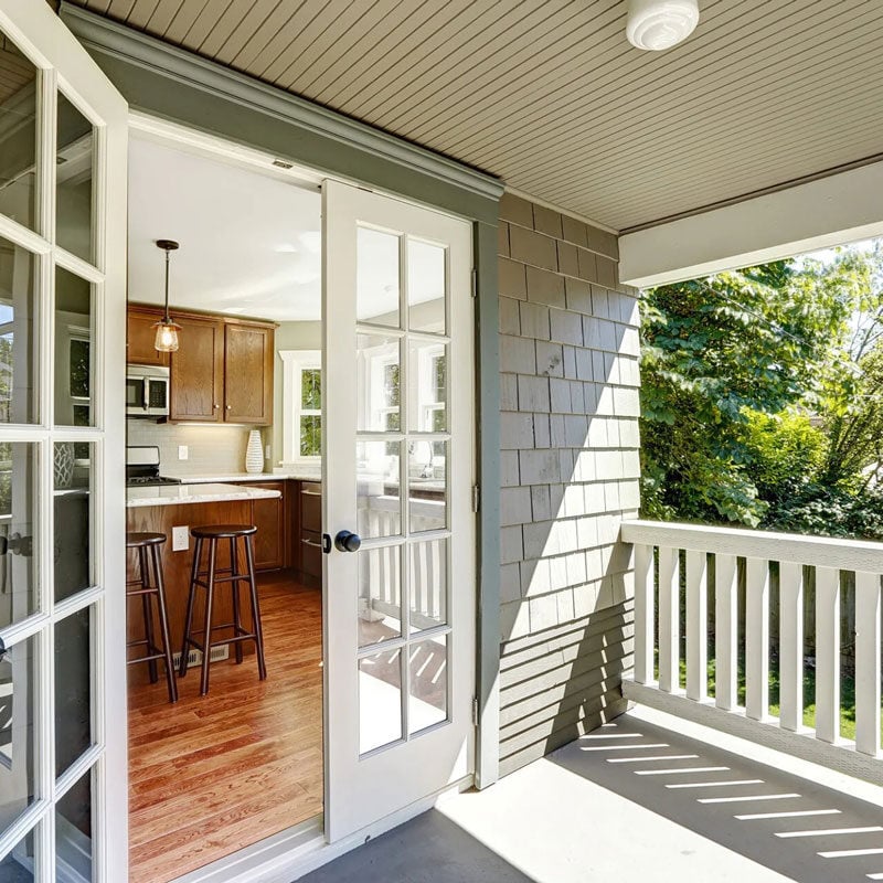 Screened in porch with white door and kitchen view Screened in porch with white door and kitchen view. The porch has a white railing and a view of trees.