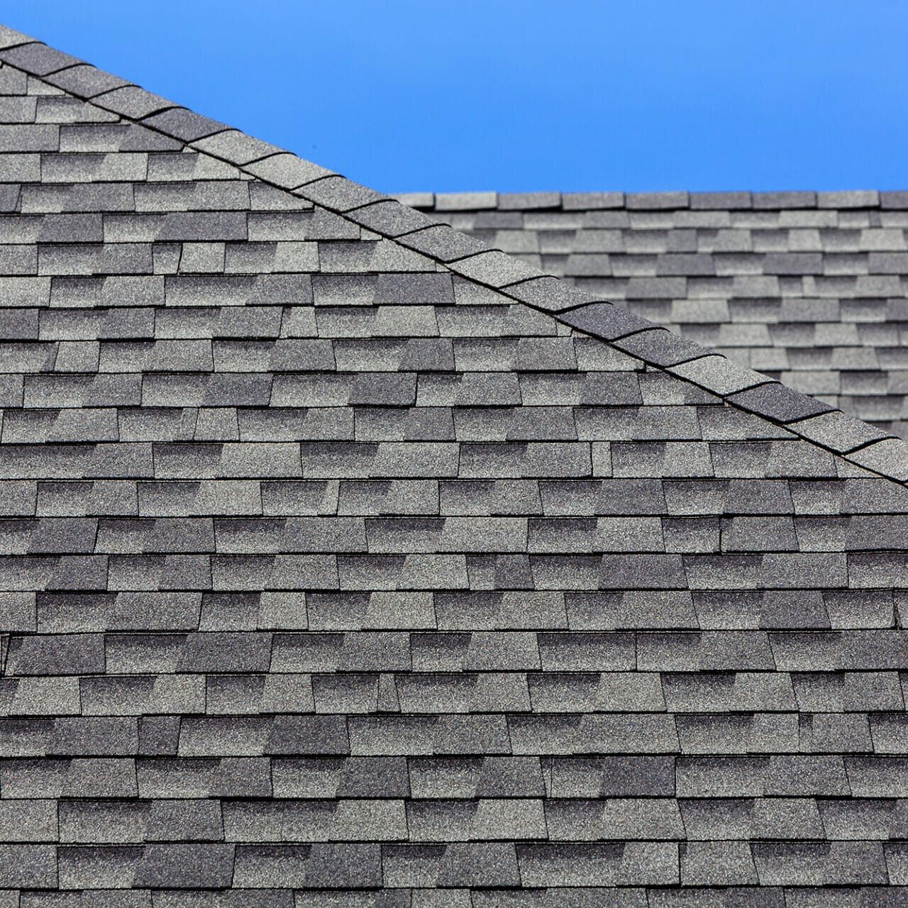 Gray roof shingles with blue sky background. A roof with shingles.