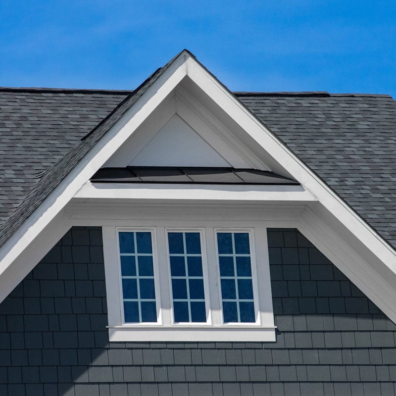 Roof with dormer window and gray shingles A roof with a dormer window and gray shingles. The window has white trim and multiple panes.