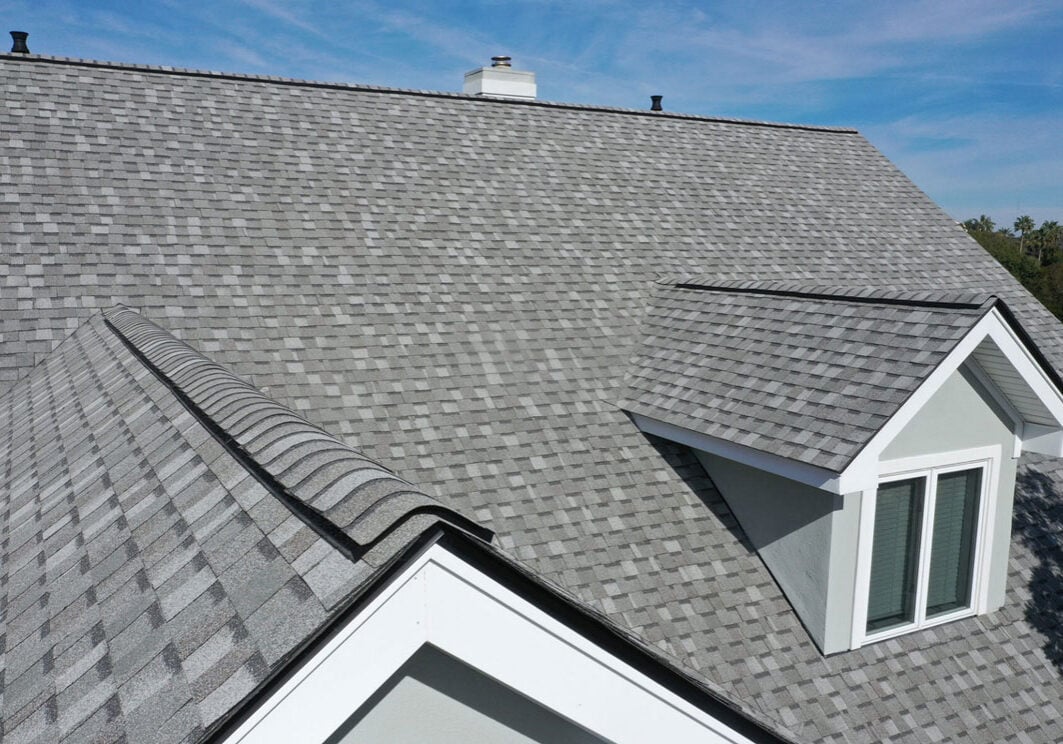 Roof with Dormer Window and Chimney A gray roof with a dormer window and chimney. The roof features a unique design.