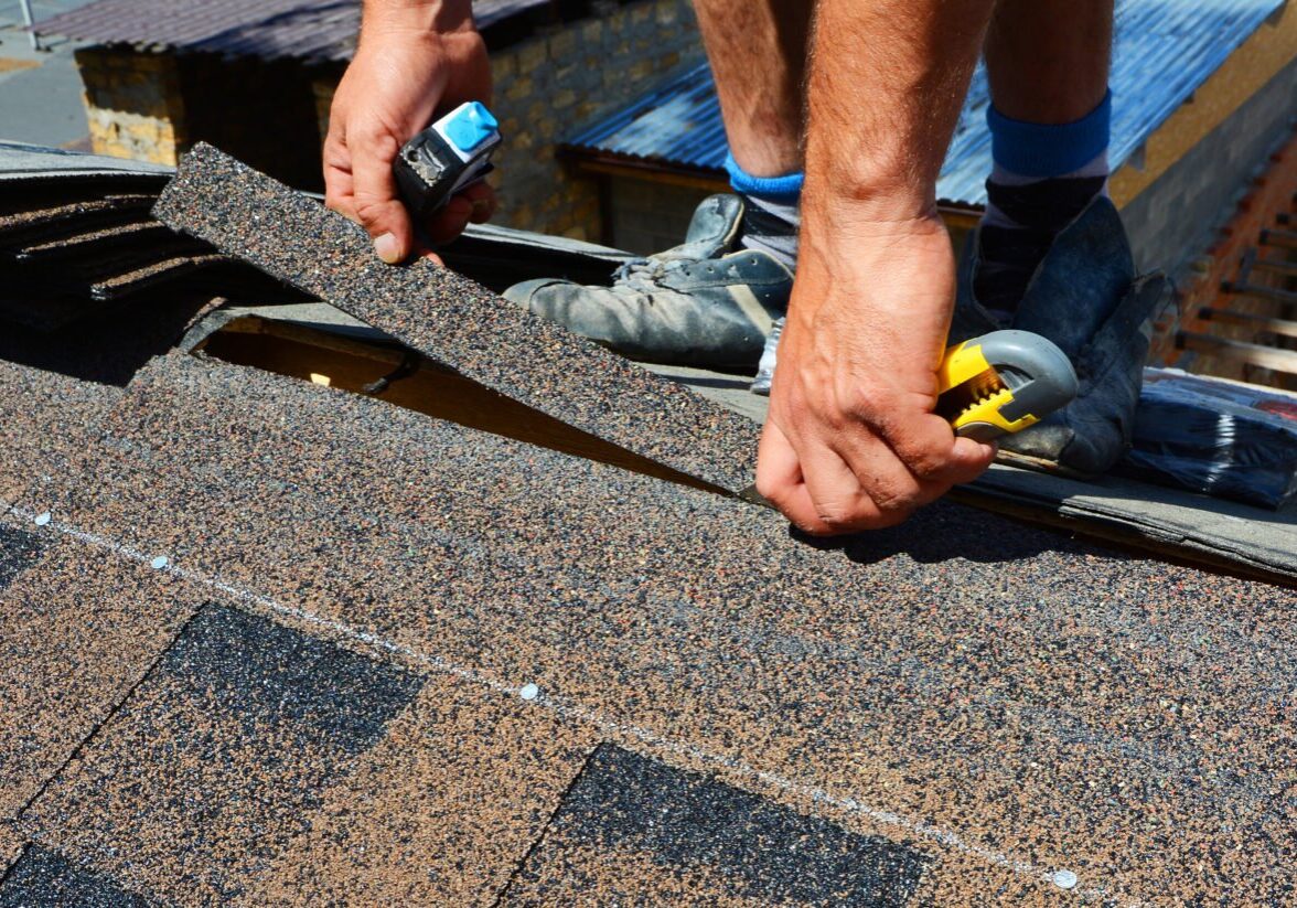 Roofing worker installing shingles on a roof A person installing roofing shingles. Roofing work in progress.
