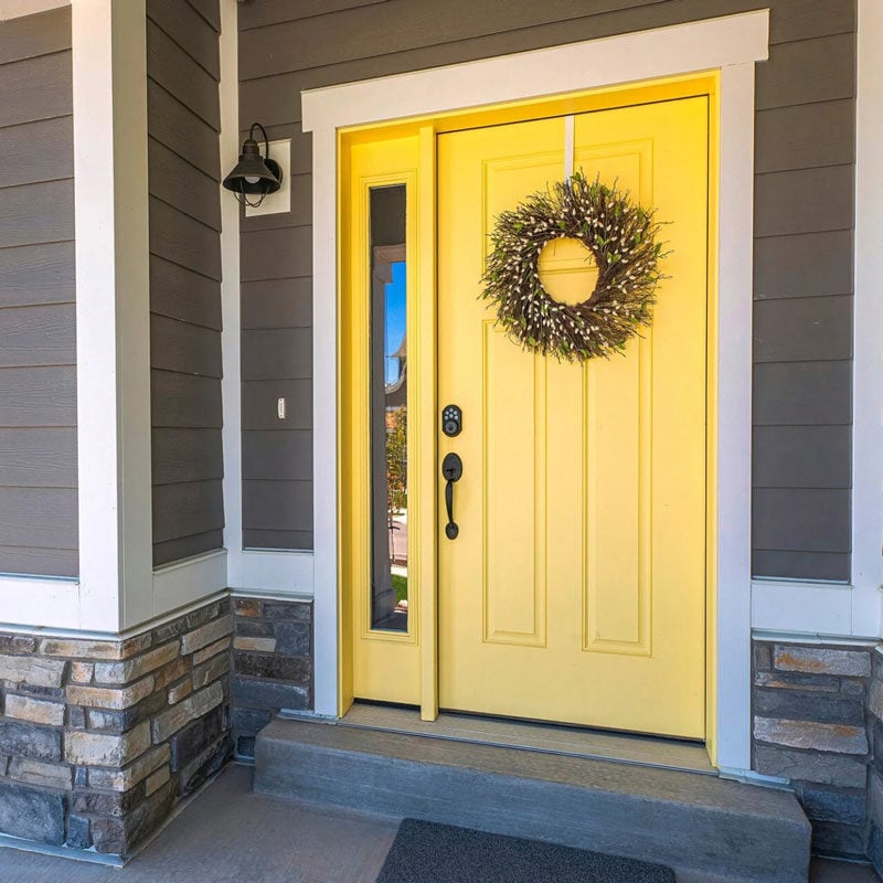 Yellow Front Door with Wreath and Sidelight A bright yellow front door with a decorative wreath and a sidelight window.